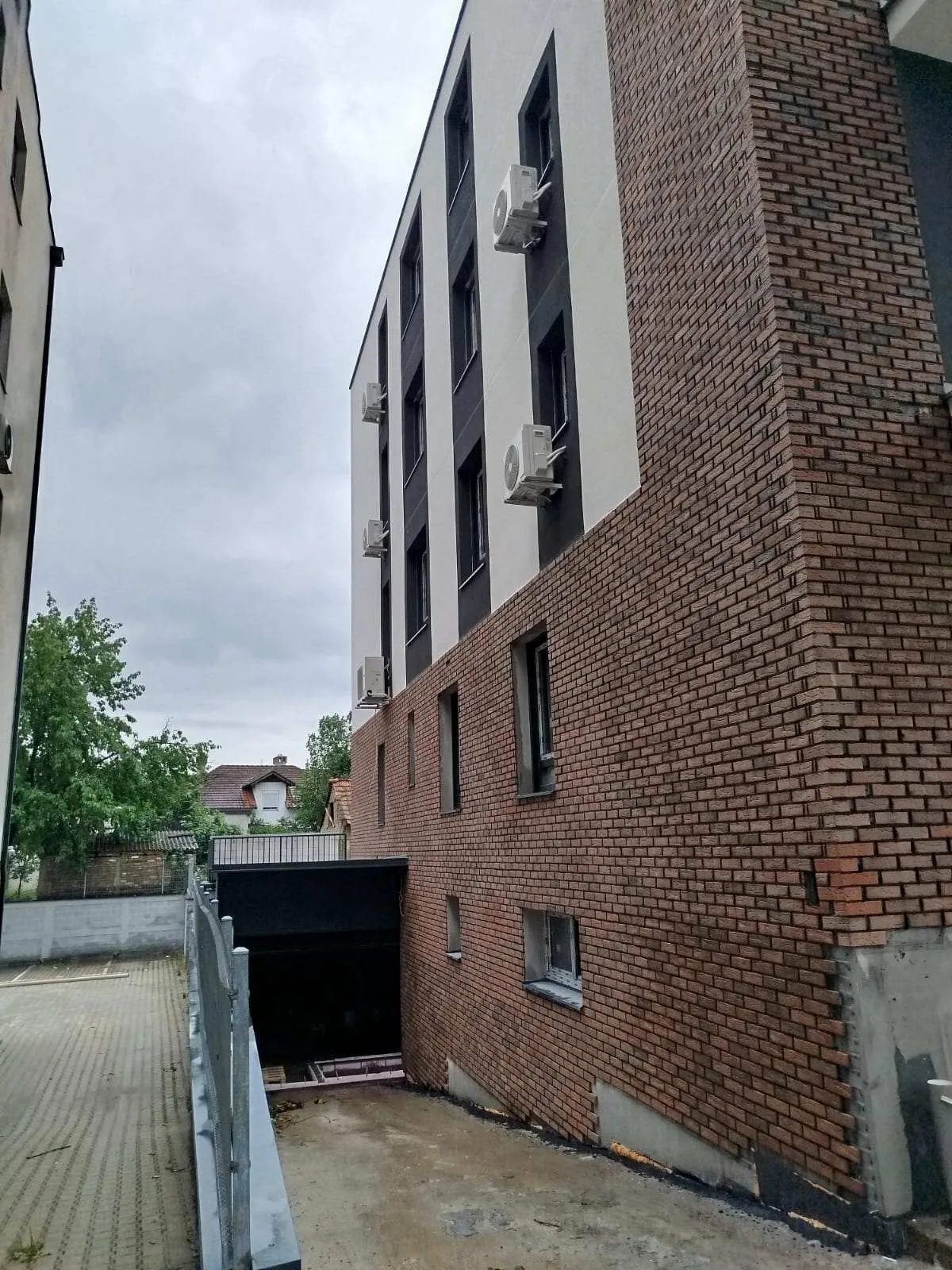 Bočna fasada novogradnje sa garažnim ulazom i uređenim parkingom — radovi Adaptera, Beograd